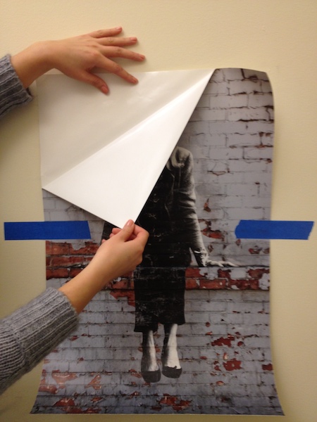 Photo of a person peeling the backing away from a Wall Peel, exposing the sticky side