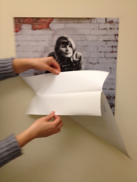 Photo of a person pulling a portion of the backing paper away from a Wall Peel